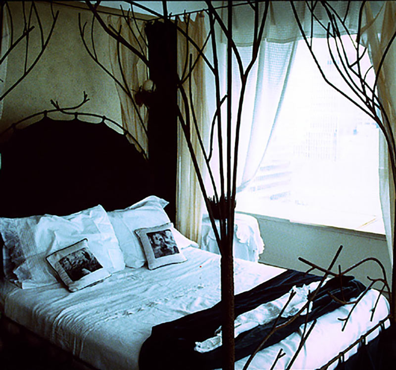 A tree bed with nest sconces and rails for curtain above. The headboard is a green velvet cushion suspended aon two sets of rails. A tree bed with nest sconces and rails for curtain above. The headboard is a green velvet cushion suspended aon two sets of rails.